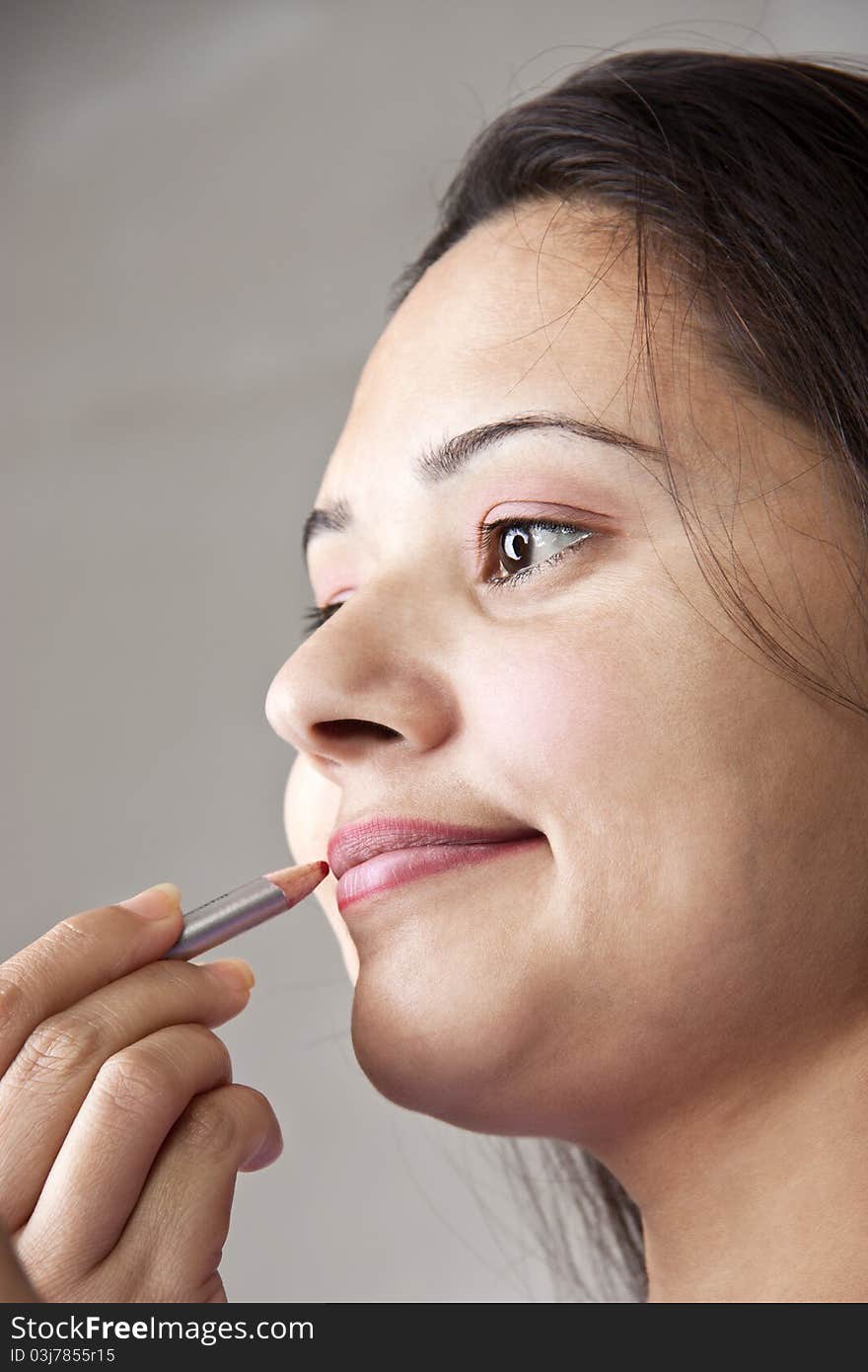 Pretty young Indian woman applying cosmetics on lips. Pretty young Indian woman applying cosmetics on lips