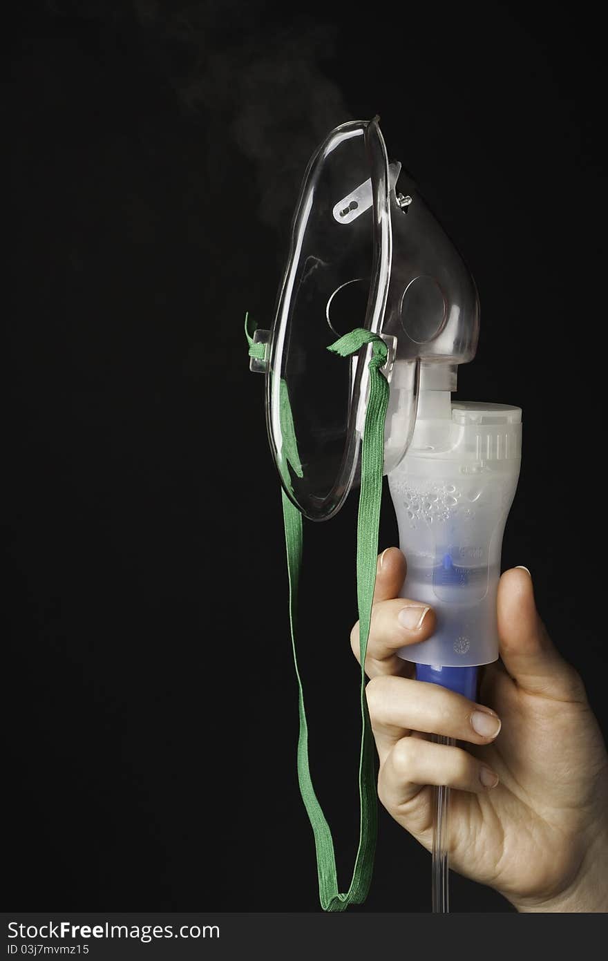 Hand with inhaler mask on a black background