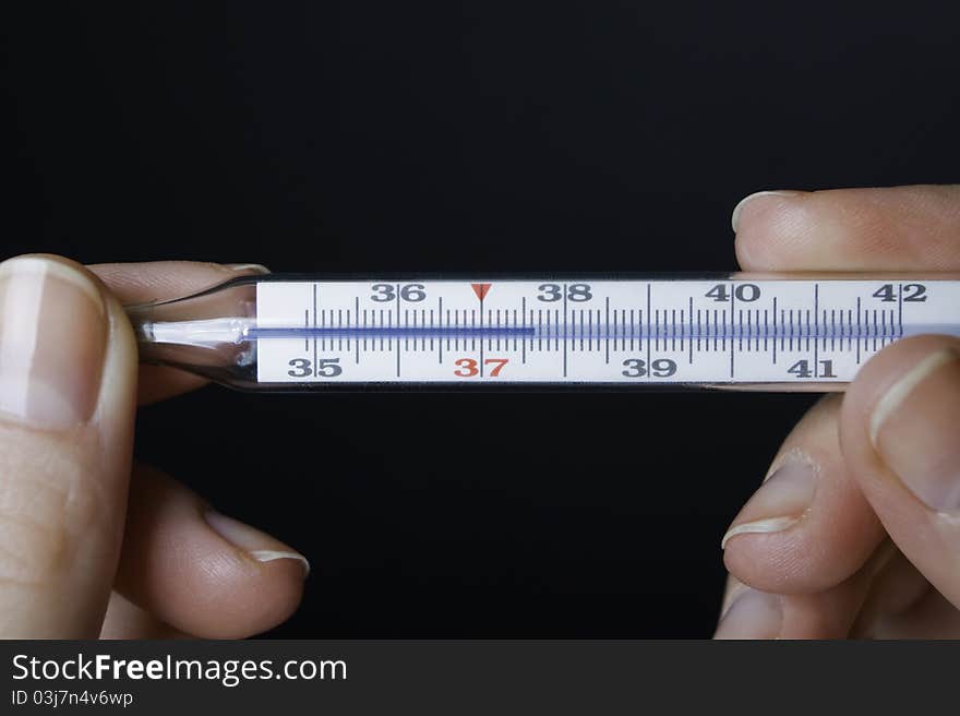 Hands with a thermometer showing thirty-seven (fever) - medical background