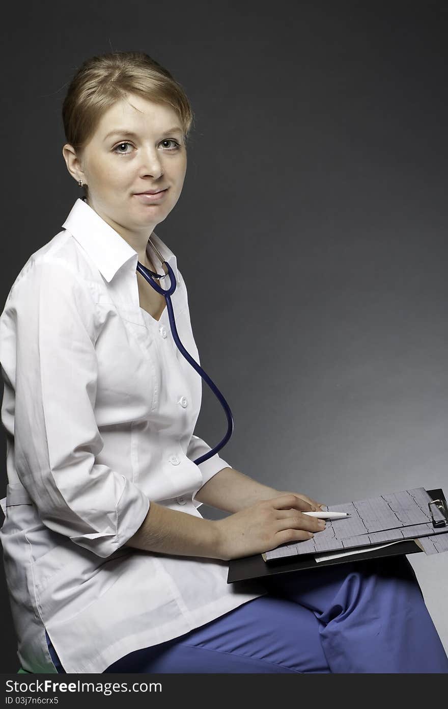 Doctor with stethoscope and electrocardiogram on a dark background (medical theme)