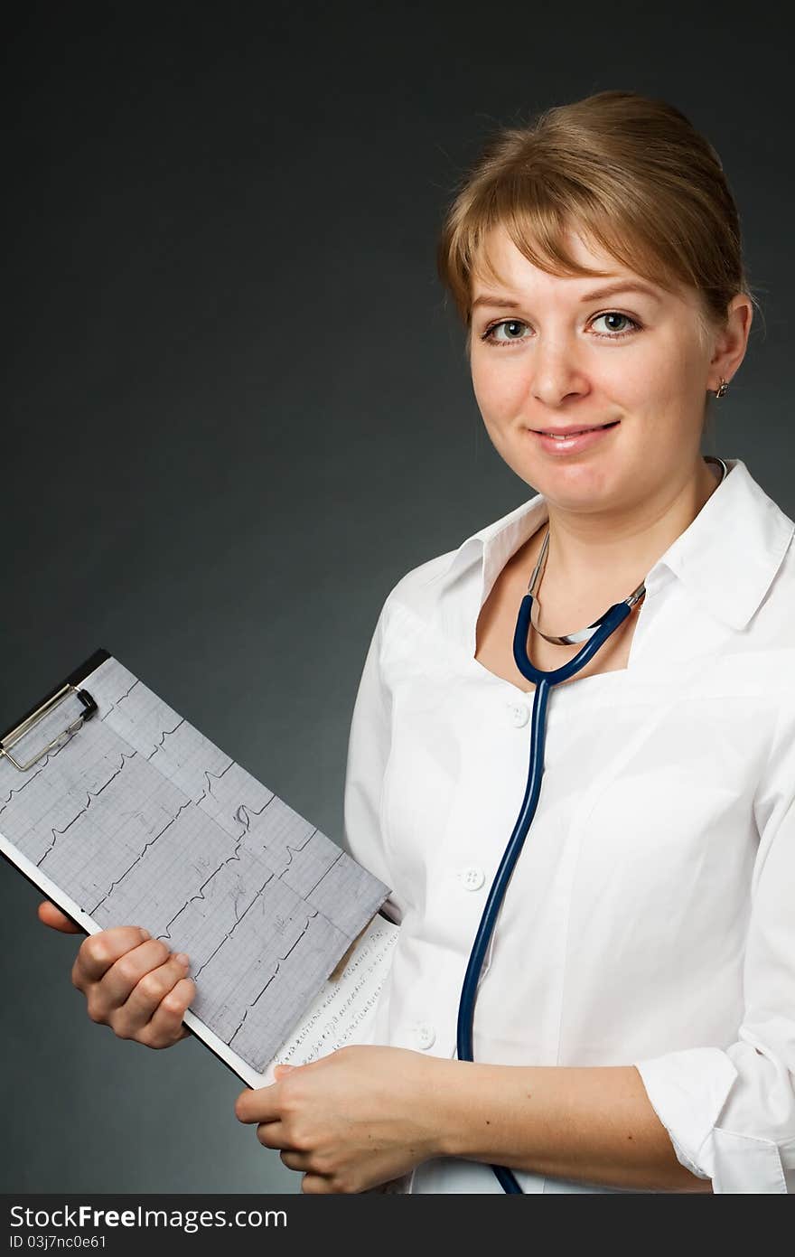 Doctor with stethoscope and electrocardiogram on a dark background (medical theme)