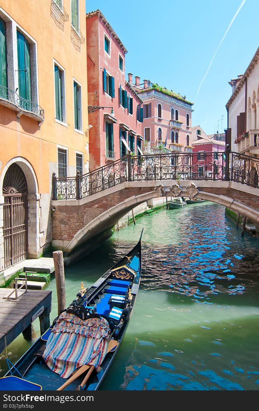 A view on canal with parked gondola in Venice,Italy. Summer in Venice. A view on canal with parked gondola in Venice,Italy. Summer in Venice.