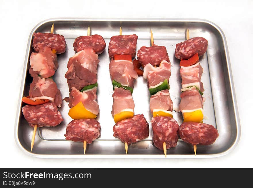 Skewers of raw meat and peppers, white background