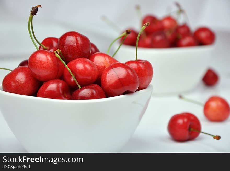 Fresh cherries in white bowls on a white background. Fresh cherries in white bowls on a white background.