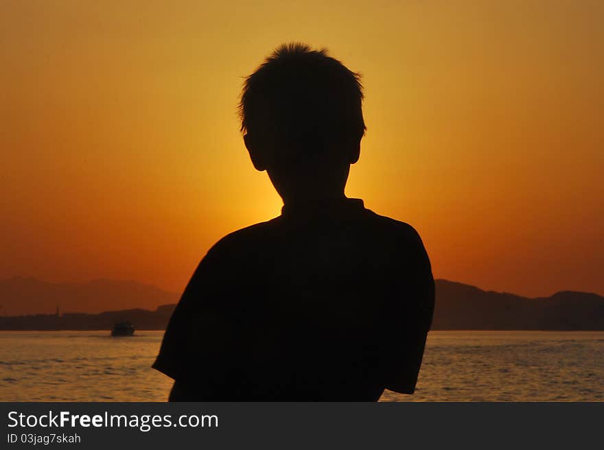 Outlined by a child on a boat at sea at sunset. Outlined by a child on a boat at sea at sunset