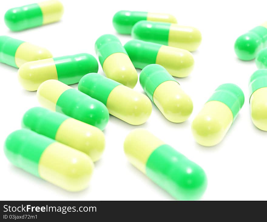 Many green-yellow pills on white background, isolated