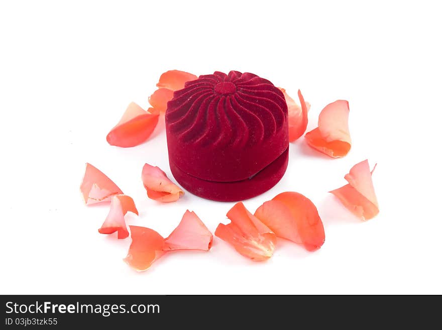 Closed box and lying next to rose petals on white background