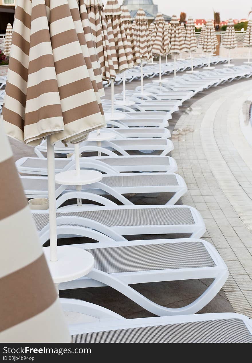 Swimming pool area of hotel with umbrella and beach chair .