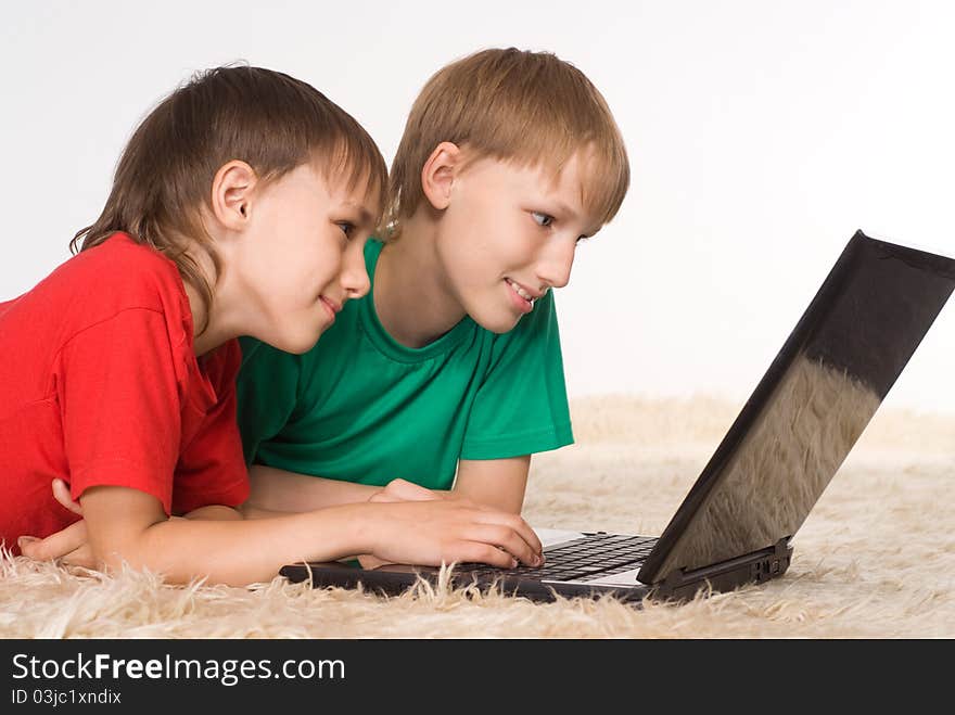 Two brothers playing at laptop on a carpet