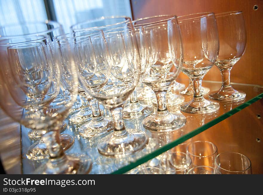 Cocktail drink glasses lined up on a glass shelf, ready to be filled and served. Cocktail drink glasses lined up on a glass shelf, ready to be filled and served.