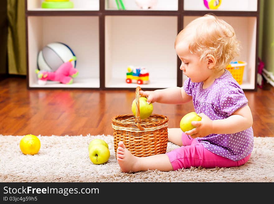 Little girl playing with apple and lemons in her room