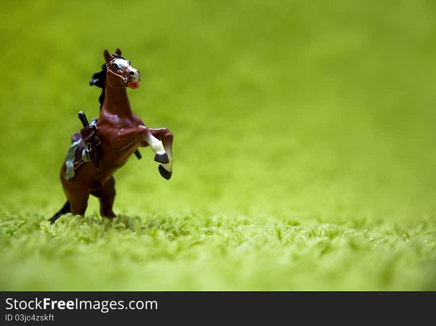 Miniature toy horse in running posture on a carpet like grass. Miniature toy horse in running posture on a carpet like grass