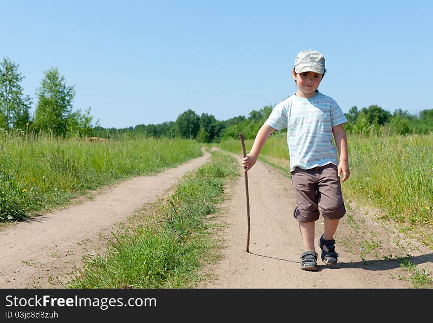 The little boy walks on rural road