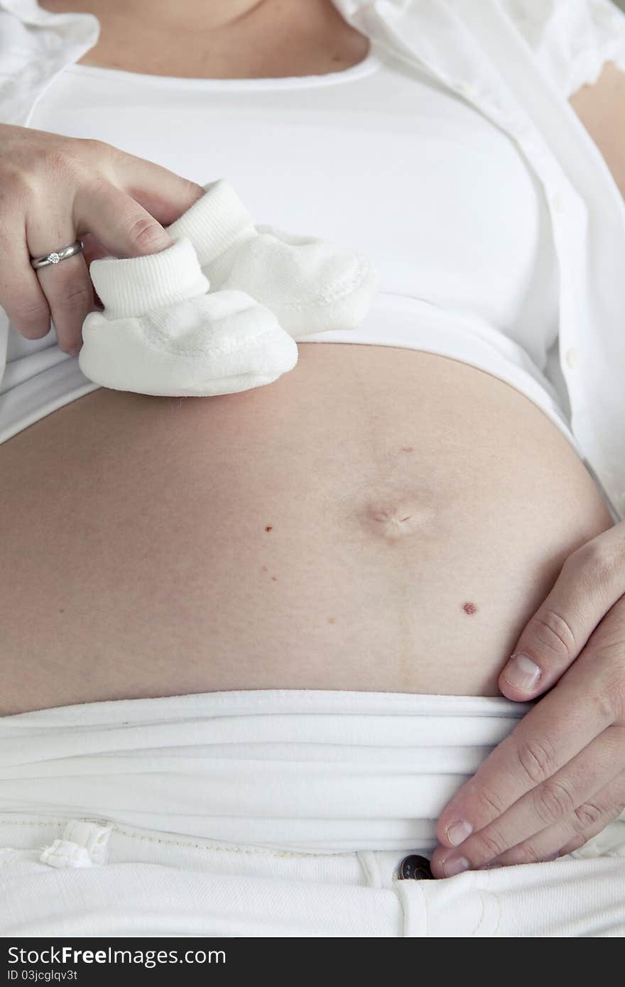 Shot of a pregnant woman with baby shoes. Shot of a pregnant woman with baby shoes