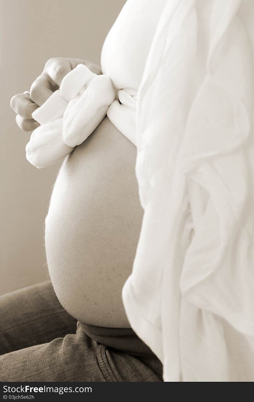 Shot of a pregnant woman with baby shoes. Shot of a pregnant woman with baby shoes