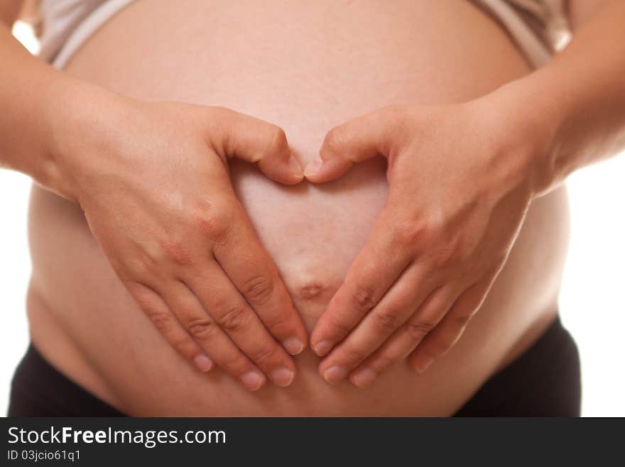 Woman's belly in 9th month of pregnancy on a white background. Hands form hart on the belly. Woman's belly in 9th month of pregnancy on a white background. Hands form hart on the belly