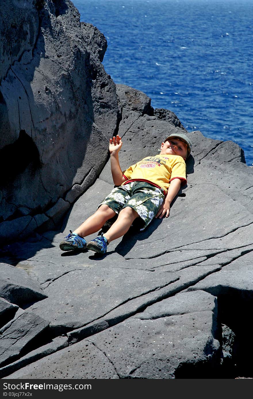 Happy boy lies on the rock