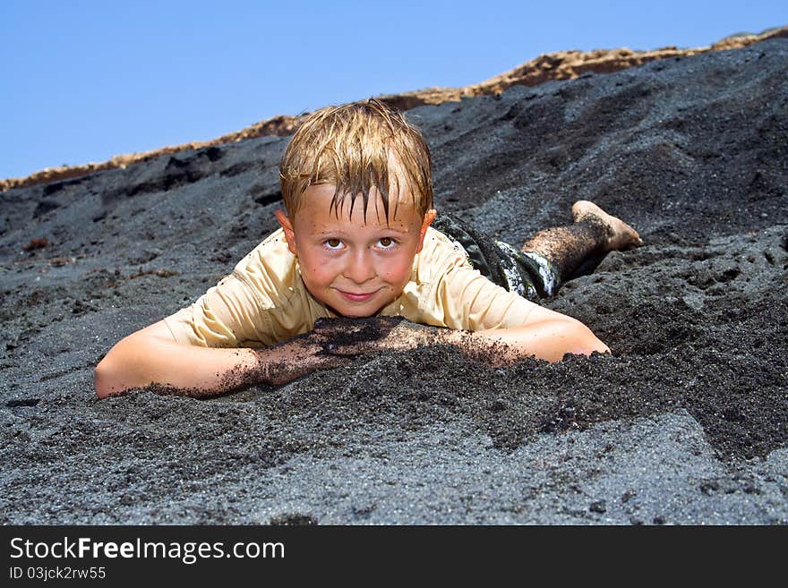 Boy has fun lying in the  black beach