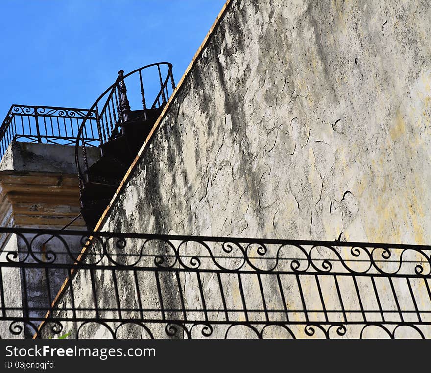 Metal spiral staircase to the roof and old flaky wall