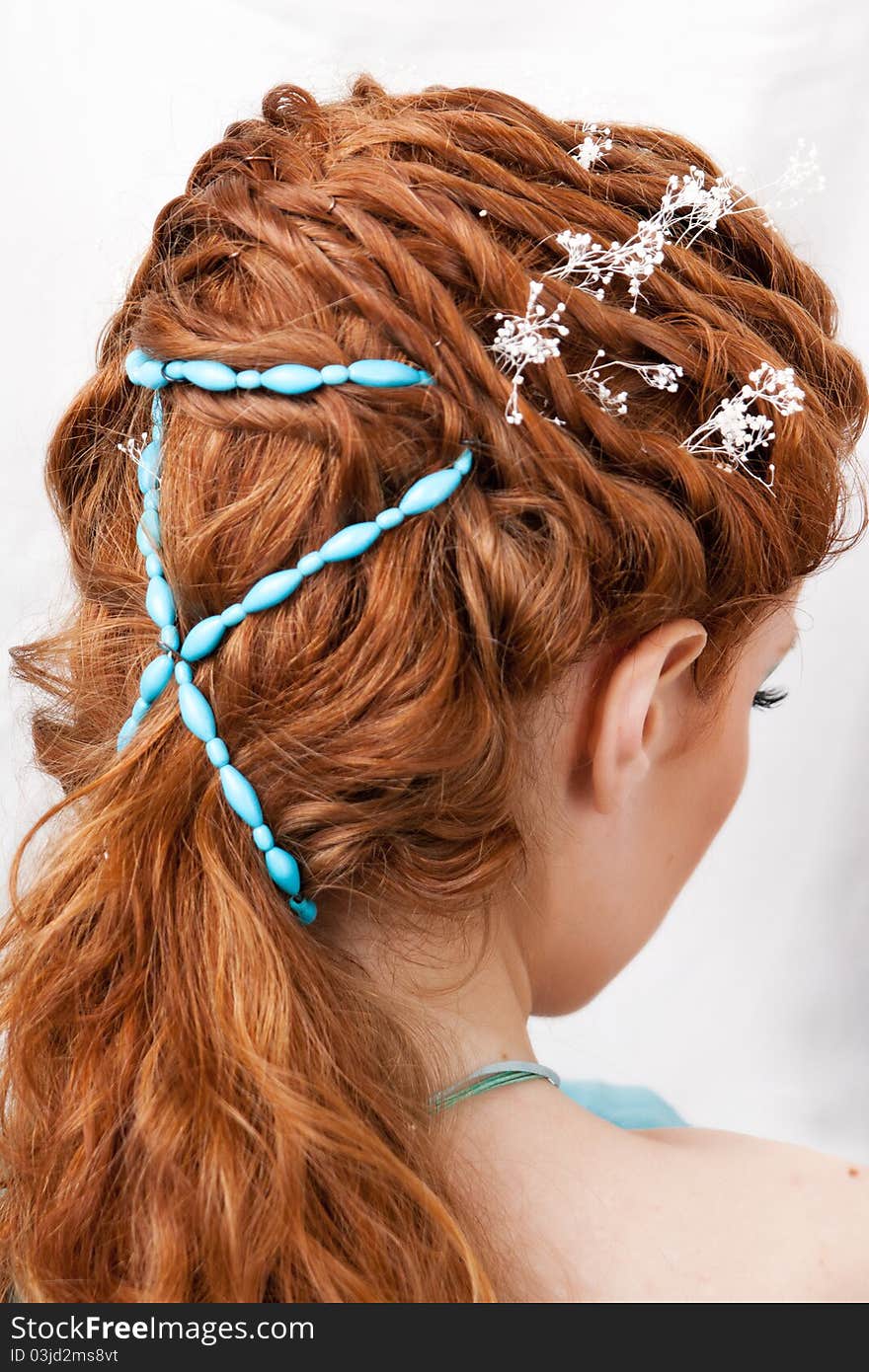 Hairdress of the red-haired girl with blue ornaments