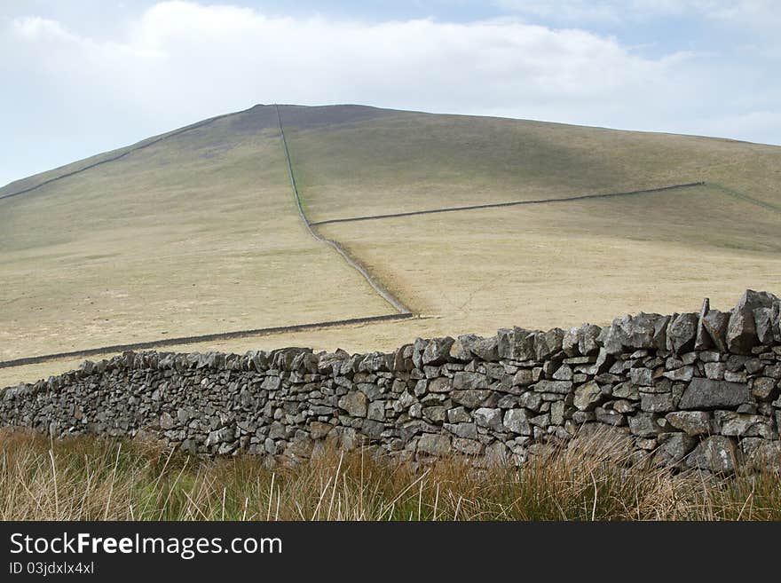 Dry stone walls make a pattern over a hillside leading to the peak. Dry stone walls make a pattern over a hillside leading to the peak.