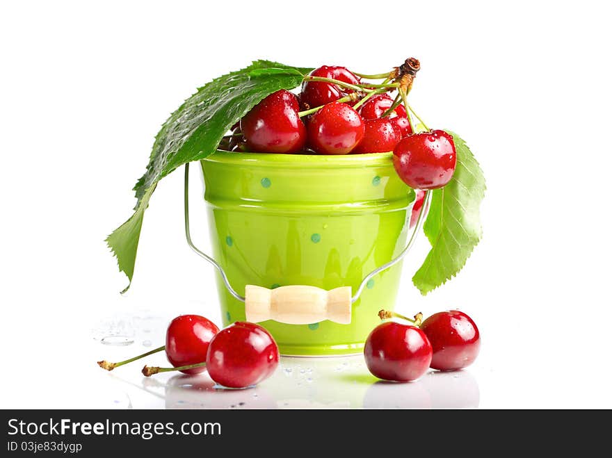 Fresh cherries with green leaves and drops in green baucket isolated on white. Fresh cherries with green leaves and drops in green baucket isolated on white