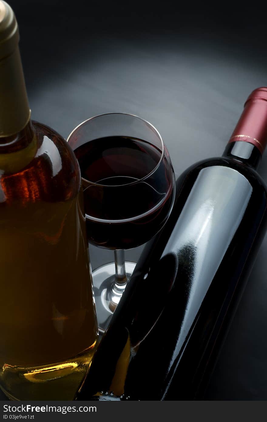 Bottle and glass of wine on a dark background