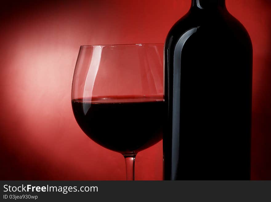 Bottle and glass of wine on a red background