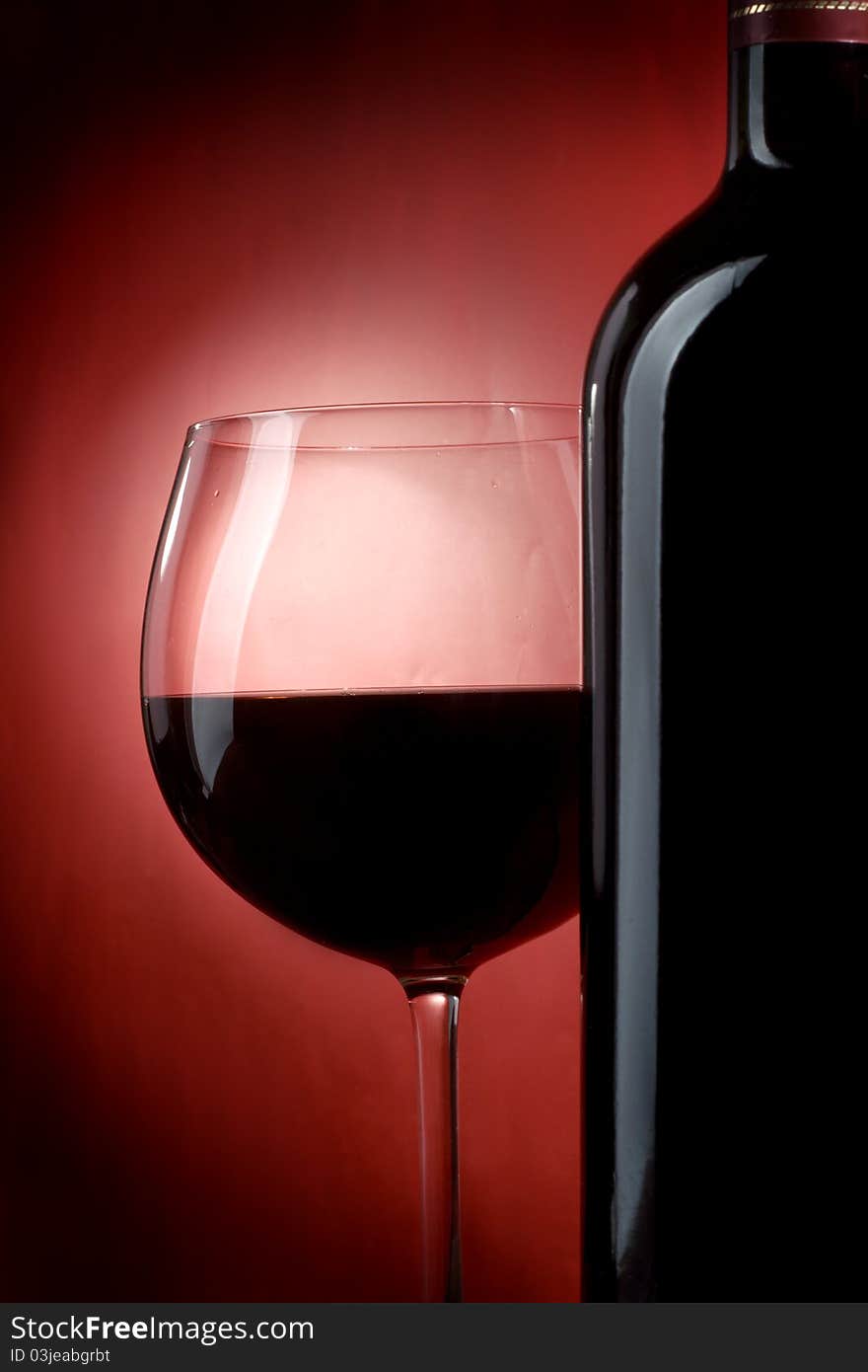 Bottle and glass of wine on a red background. Bottle and glass of wine on a red background