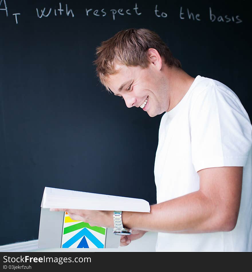 Handsome college student solving a math problem during math class in front of the blackboard/chalkboard (color toned image)