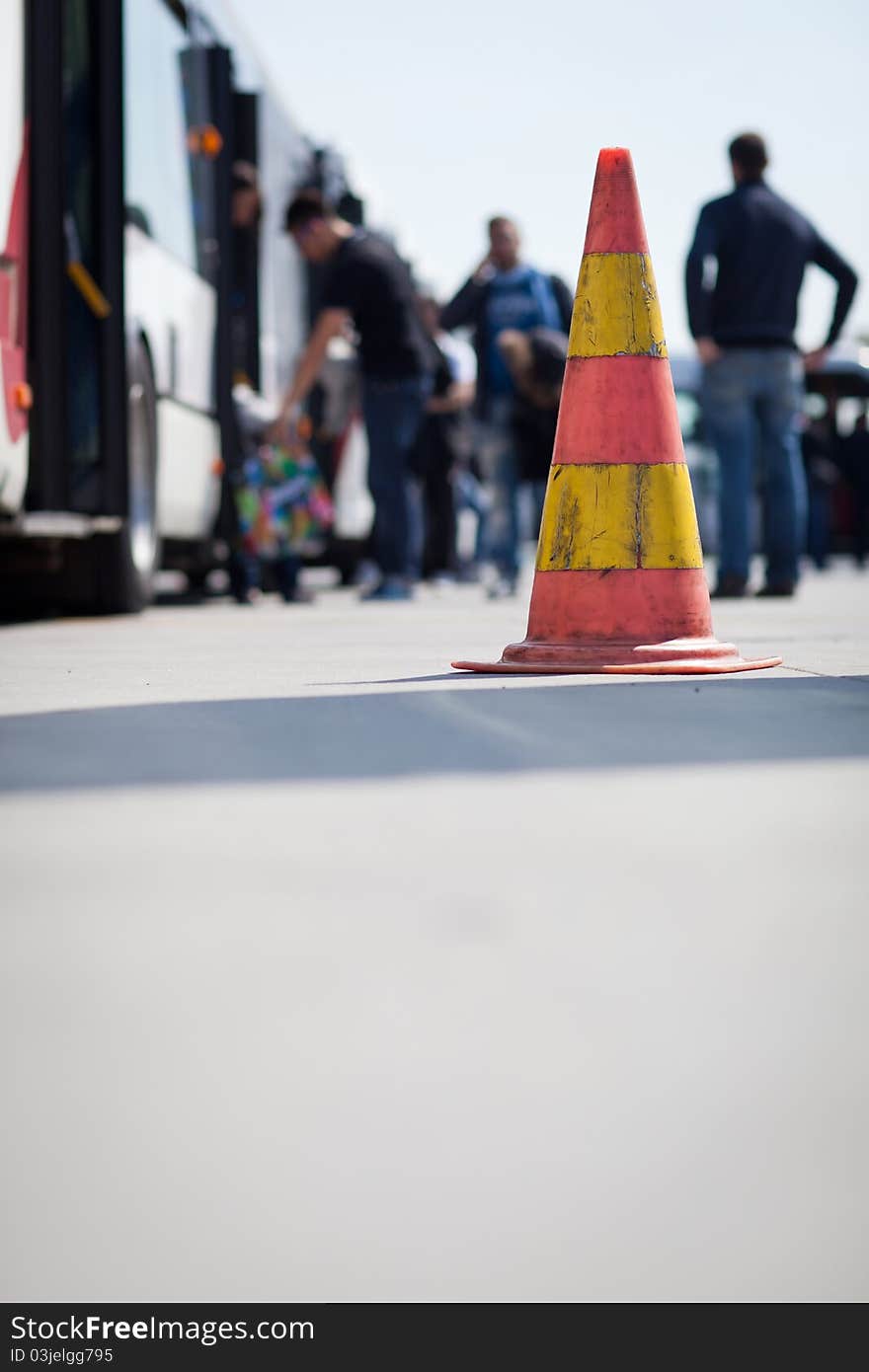 Safety cone at the aerodrome of an airport (with passengers getting on a shuttle bus in the background)