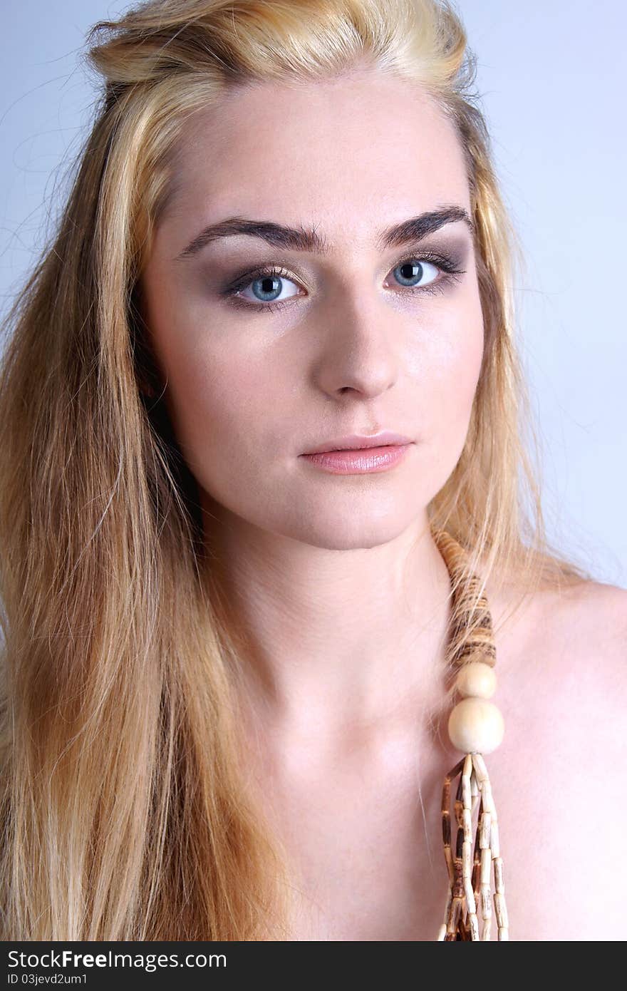 Portrait of pretty blond girl wearing wooden beads, closeup.