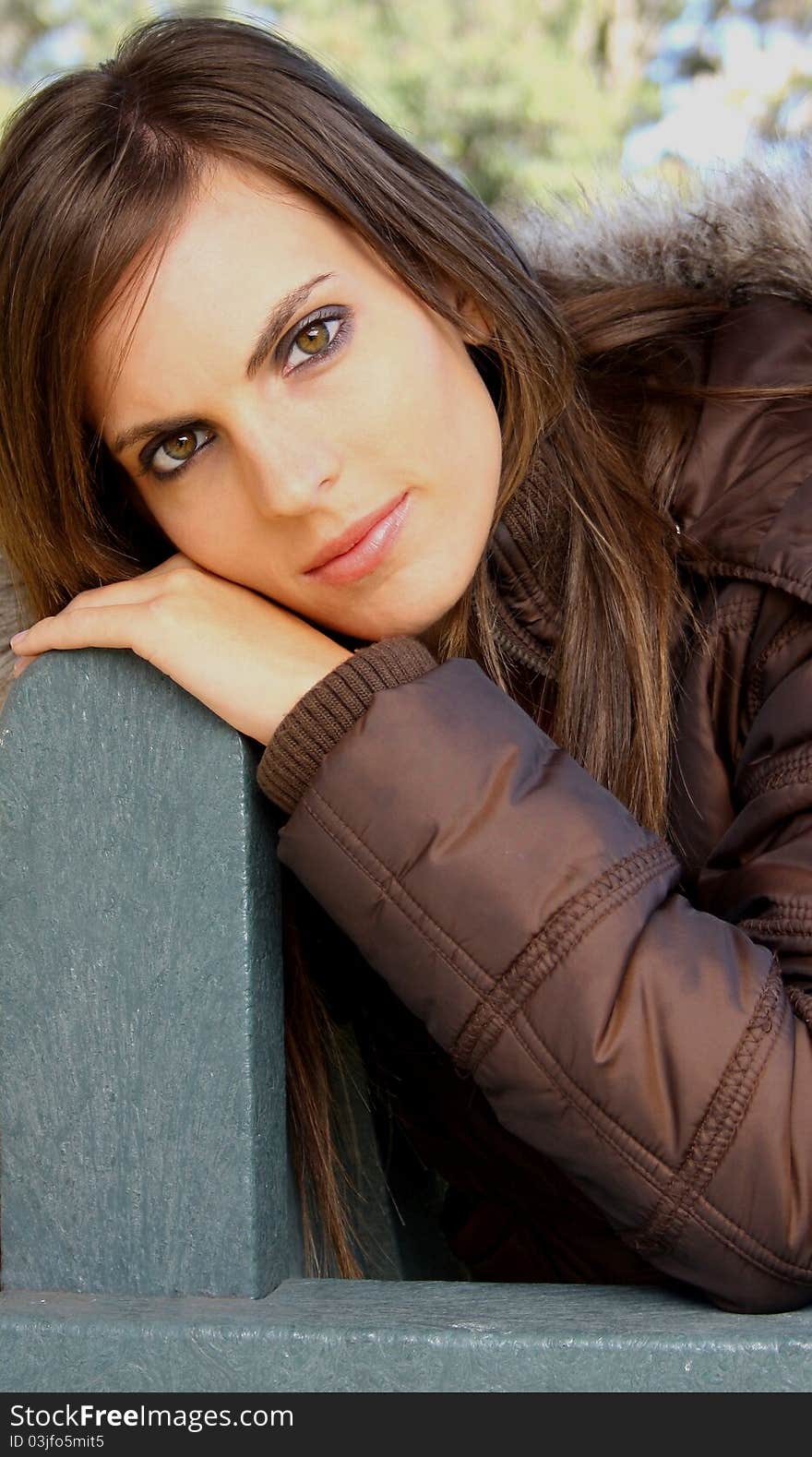 Attractive lady sitting on green park bench