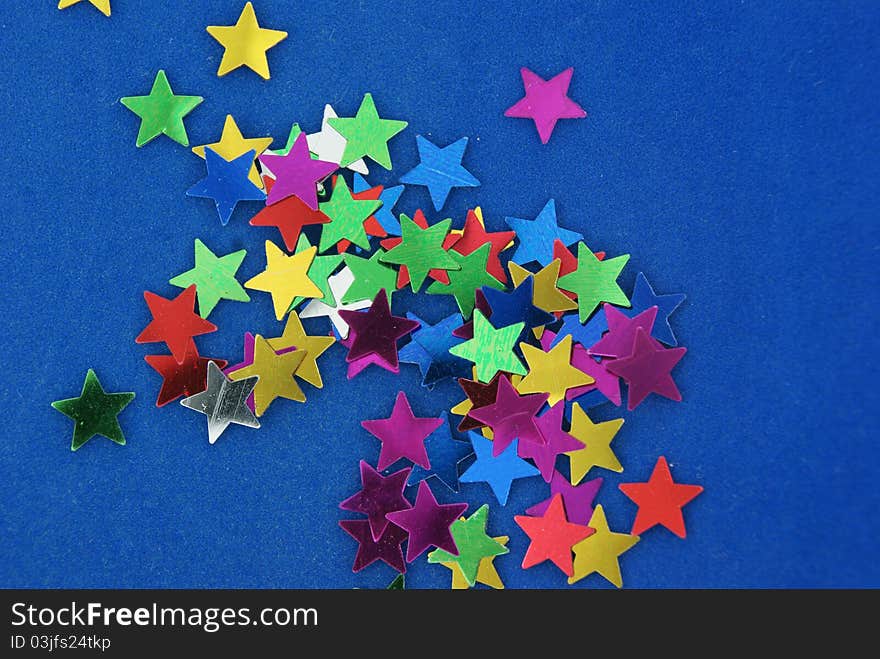 Glittering multicolored stars on blue background. Glittering multicolored stars on blue background