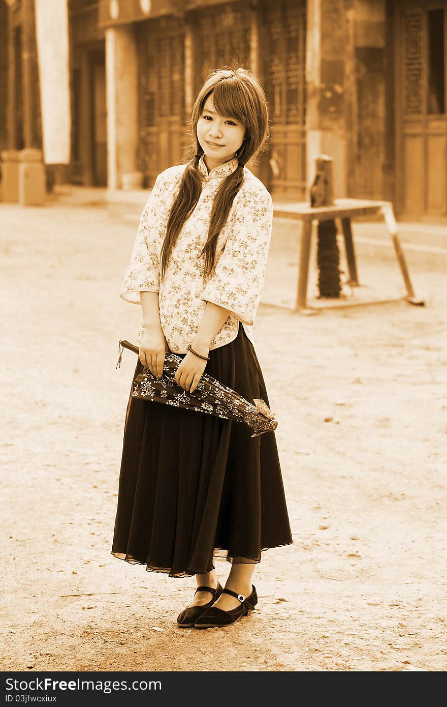 Chinese girl in traditional dress standing on Chinese ancient street.