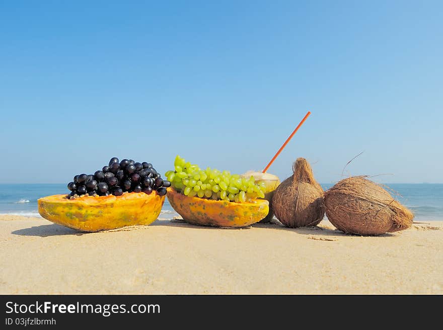 Papaya, coconut, nut and grapes on the sand. Papaya, coconut, nut and grapes on the sand