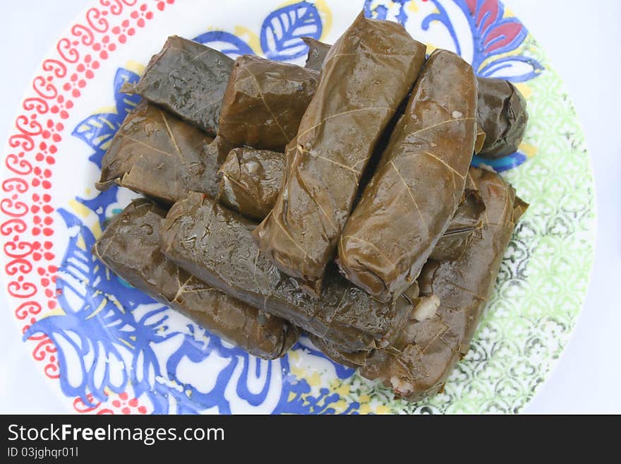 Pile of stuffed grape leaves on a plate.