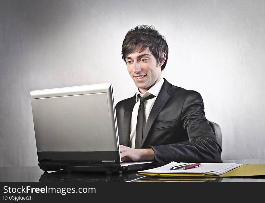 Smiling young businessman using a laptop. Smiling young businessman using a laptop