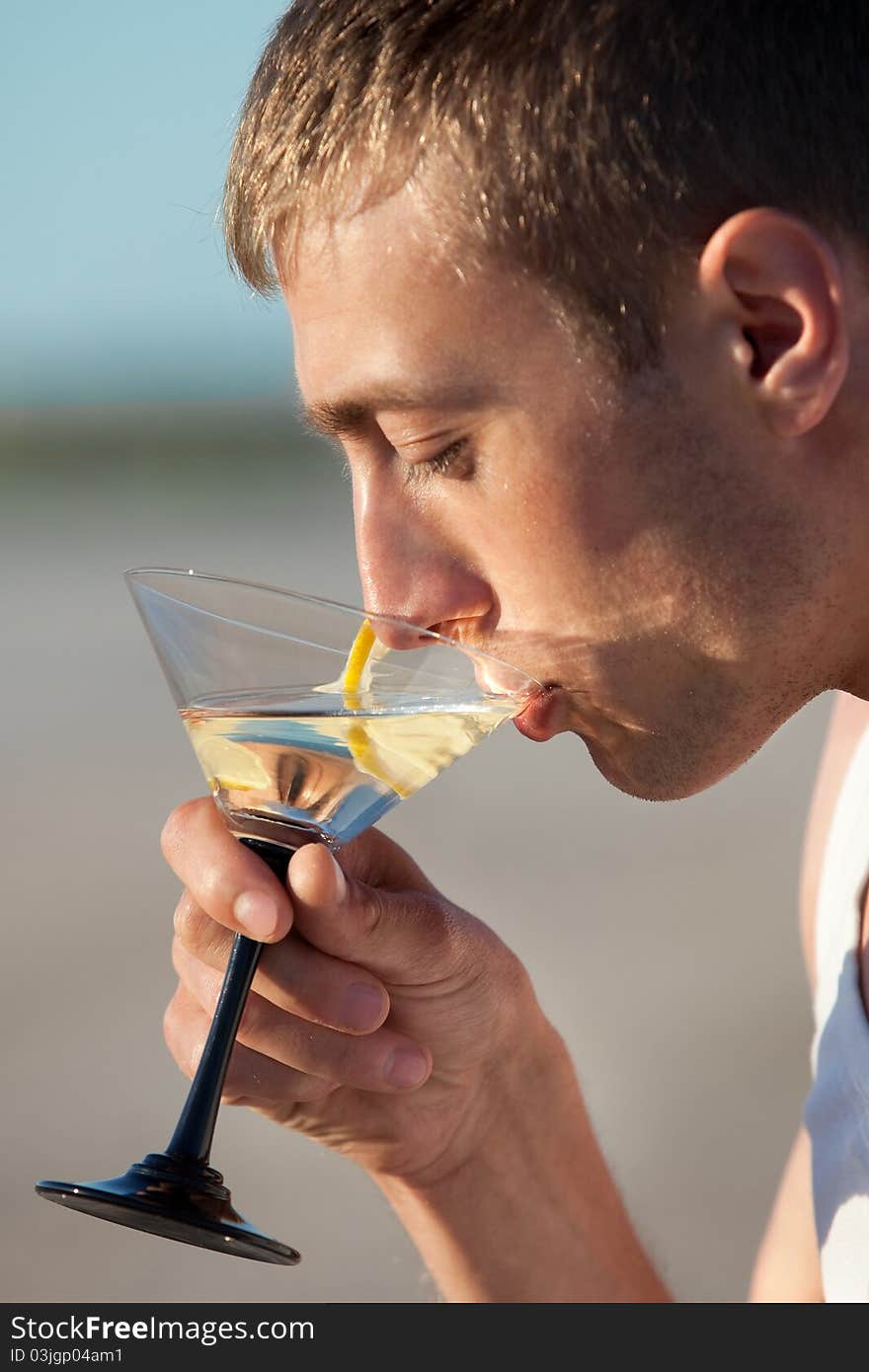 Portrait of guy drinking cocktail on beach