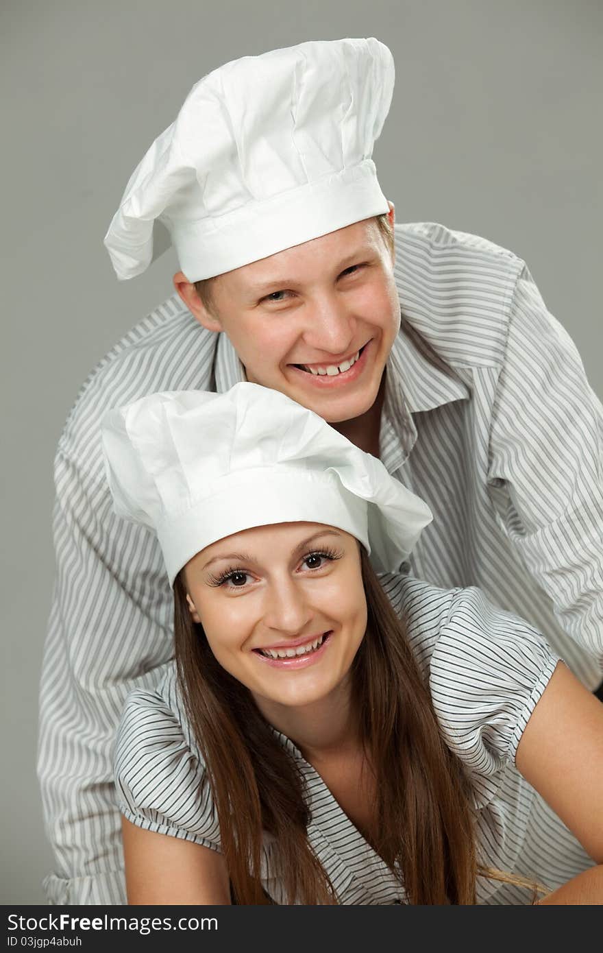 Young loving couple cooks. Over gray background