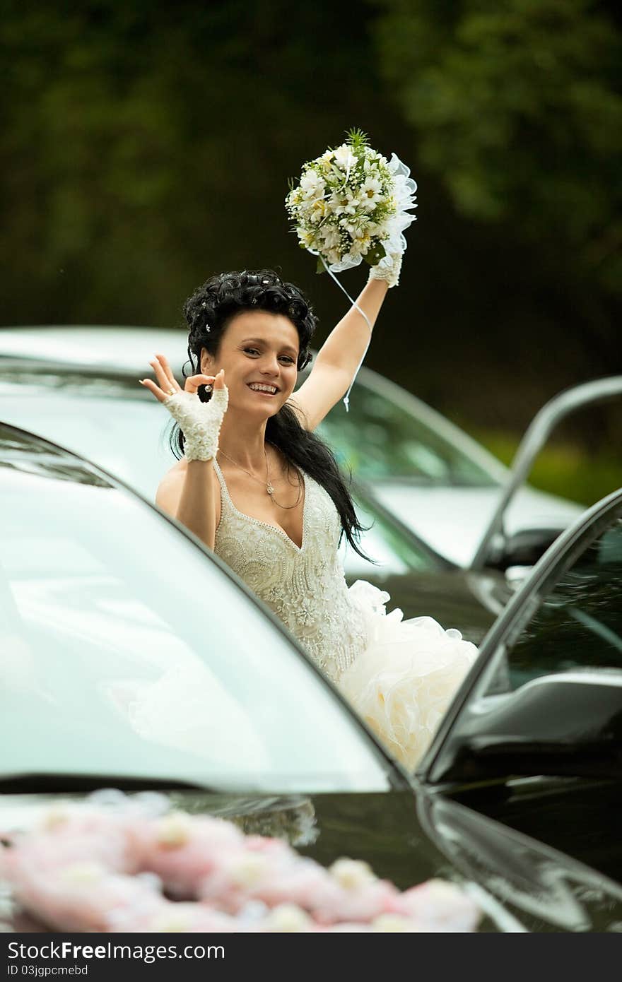 Portrait of the bride near the car showing 'ok' gesture. Portrait of the bride near the car showing 'ok' gesture