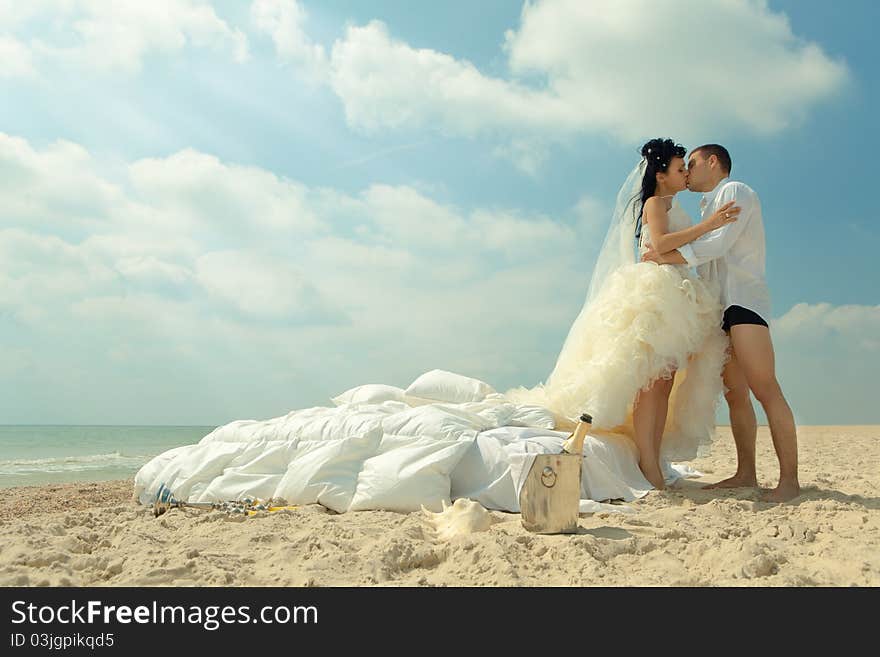 Bride and groom kissing next to bed on the beach. Bride and groom kissing next to bed on the beach