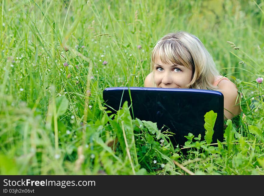 Young woman with a laptop on the grass