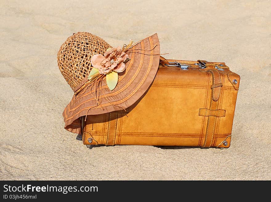 Suitcase and straw hat on a sea-shore