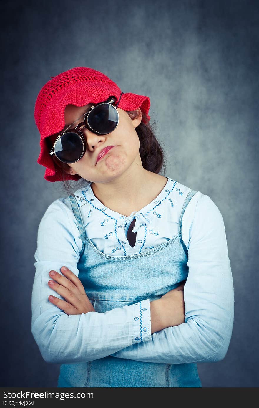 Little girl in red hat looking disappointed and fold her arms. Little girl in red hat looking disappointed and fold her arms