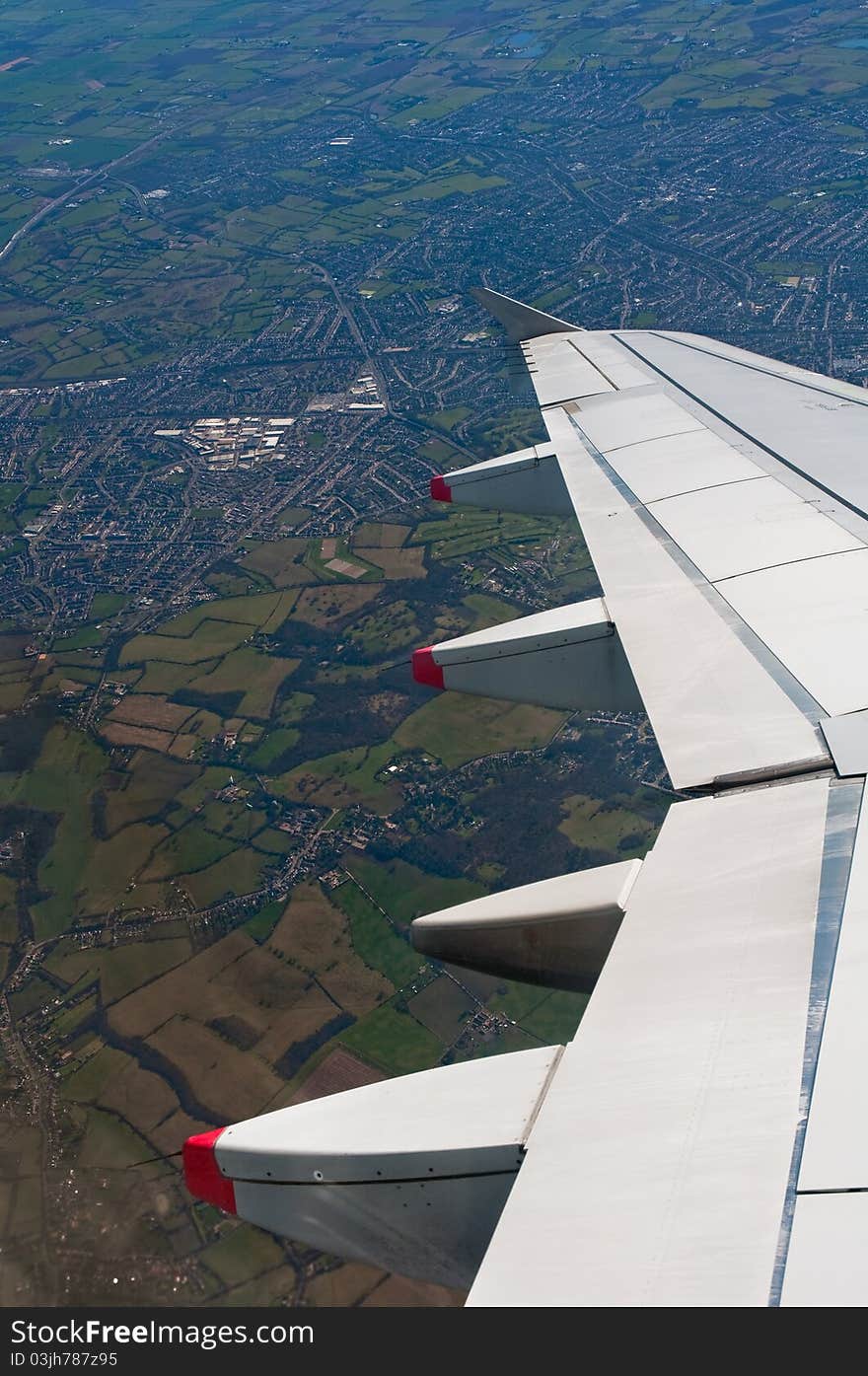 Airplane wing detail, flying over countryside, vertical composition. Airplane wing detail, flying over countryside, vertical composition