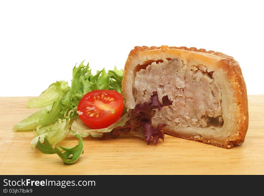 A portion of pork pie with salad garnish on a wooden food preparation board