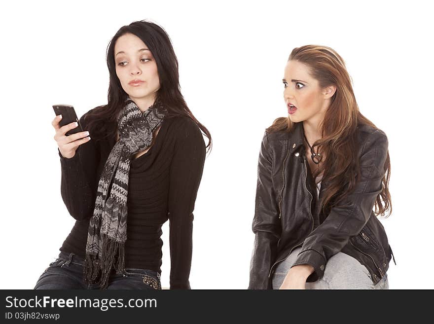 A women is showing her shocked expression on her face at what the other women is texting on her phone. A women is showing her shocked expression on her face at what the other women is texting on her phone.