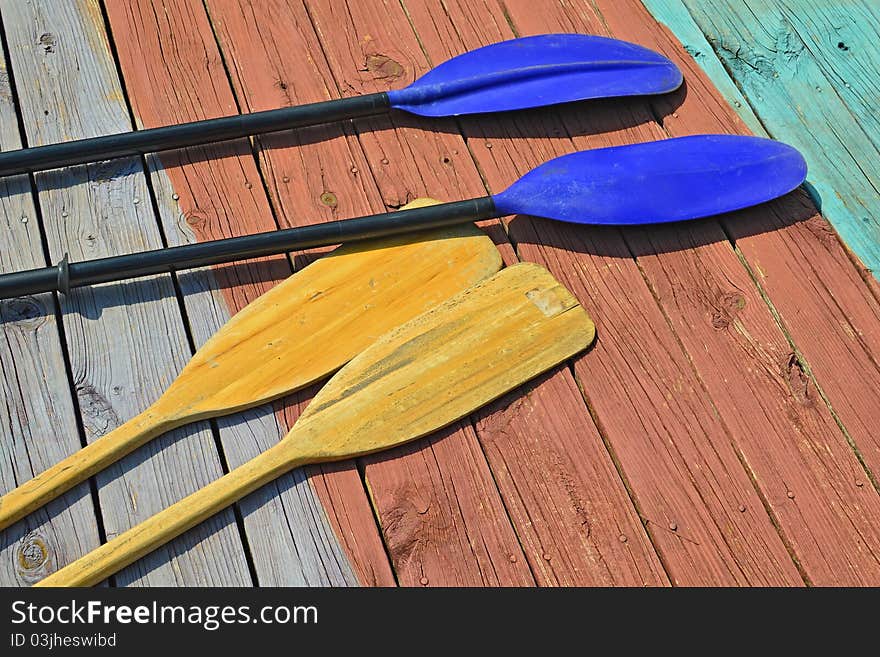 Canoe paddles and kayak oars on a wooden boat dock. Canoe paddles and kayak oars on a wooden boat dock