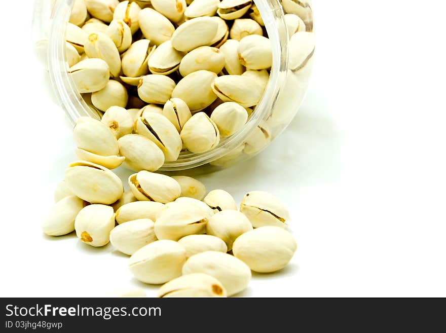 Pistachios pouring from jar on white background